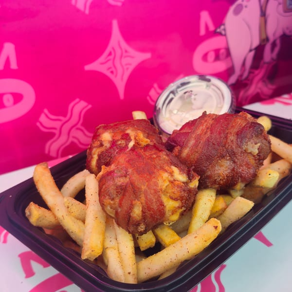 Bacon-wrapped appetizers and french fries in a black tray, with a pink Bacon Mania background.